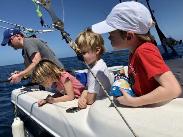 Father and children fishing from boat