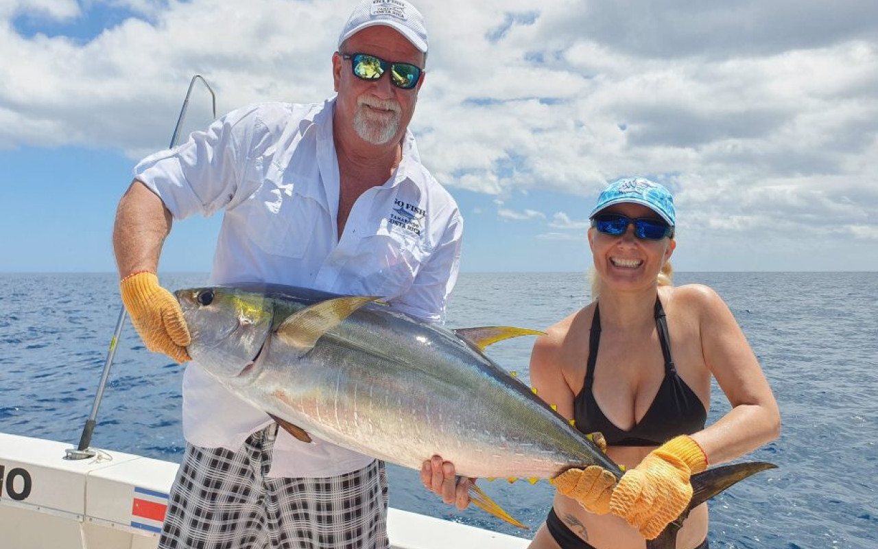 Couple holding fish together on boat